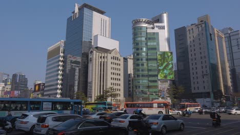 Seoul-day-traffic-at-Gangnam-station-crossroads-with-cars-moving-on-a-multilane-freeway-against-high-rise-buildings-on-sunny-day