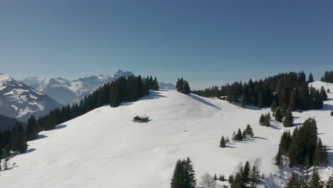 Luftaufnahme-Einer-Einzelnen,-Abgelegenen-Hütte-In-Einer-Schneebedeckten-Berglandschaft