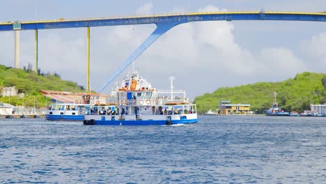 Ferries-crossing-over-Sint-Annabai-canal-below-the-Queen-Juliana-Bridge-in-Willemstad,-Curacao