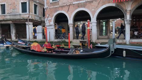 Gondolas-and-gondoliers-waiting-for-tourists-at-Sotoportego-Falier-in-Venice,-Italy