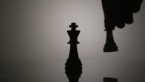 Feminism-overthrowing-the-patriarchy-concept,-queen-checkmating-the-king,-chess-pieces-backlit