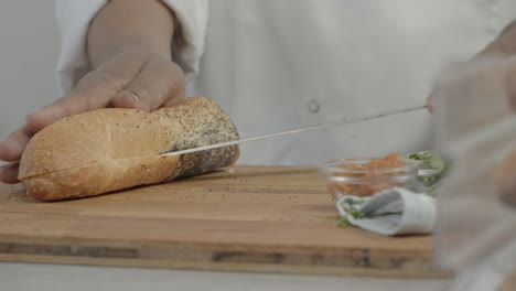 Man-Cutting-a-Piece-of-Bread-with-a-Knife-in-the-Kitchen-on-a-Sunny-Day-Shot-on-Red-Camera