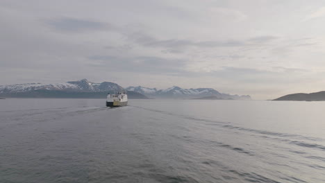 Ferry-crossing-fjord-in-arctic-ocean,-sunset-drone-view
