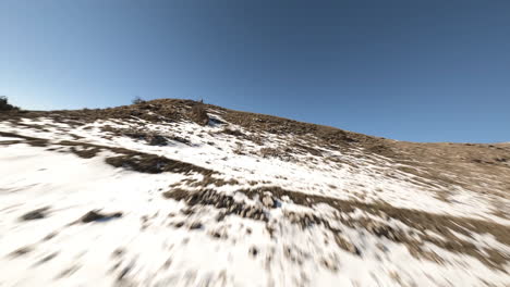 Flying-close-to-a-tree-at-high-speed-in-a-snow-covered-mountains-landscape