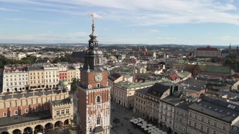 Aerial-drone-view-of-the-clock-tower-in-Krakow's-main-square-and-old-city-in-the-background-at-sunny-day