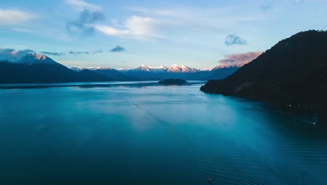 Aerial-dolly-out-hyperlapse-of-Lake-Todos-Los-Santos,-southern-Chile-with-boats-sailing,-mountains-with-snowcapped-peaks