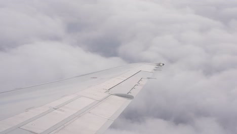 Stetige-Aufnahme-Eines-Flugzeugflügels,-Der-Am-Nachmittag-über-Den-Wolken-Fliegt
