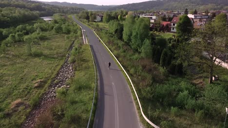 man-roller-skating-on-empty-road,-sunset,-cinematic-aerial-shot