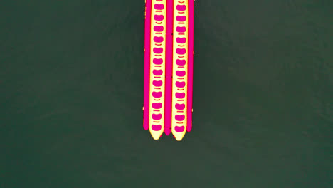 Aerial-birdseye-top-down-flying-over-empty-colorful-banana-boats-and-speedboat-on-coast-of-Ubatuba