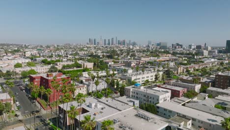 Drone-Above-Los-Angeles-Neighborhood-in-Day-Time,-LA-Skyline-on-Horizon-and-Apartment-Rooftops-Below