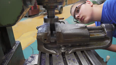 Young-male-student-intently-practising-how-to-use-a-metal-lathe-at-a-vocational-high-school-workshop