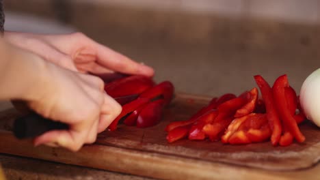 women-in-the-yellow-clothes-cutting-bulgarian-sweet-red-pepper-with-a-sharp-knife-for-cooking