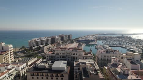 Aerial-towards-Alicante-Marina-flyover-Downtown-buildings,-By-Mediterranean-Sea