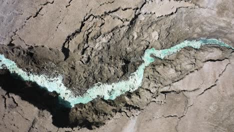 Dead-Sea-Hot-Springs-aerial-top-down-shot-fast-zoom-in-over-desert-canyon-landscape-with-crystal-clear-aqua-colored-warm-waters
