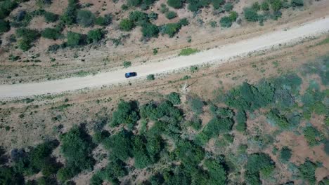 Aerial-tracking-shot-of-jeep-driving-on-dirt-road-over-remote-wasteland-in-Africa