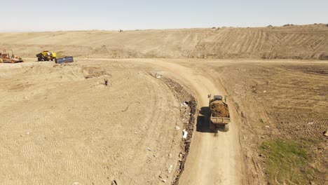 Cargo-truck-transporting-soil-to-prepare-landfill-parcel,-aerial-drone-view