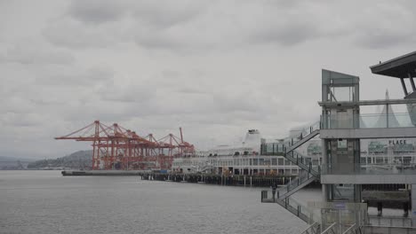 View-of-Iconic-Canada-Place-building,-Vancouver-port-and-red-cranes-on-an-overcast-day,-British-Columbia,-Canada