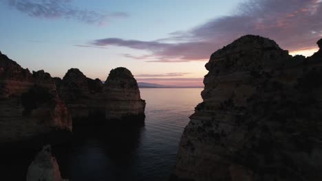 Drohne-Fliegt-Zwischen-Felsformationen-Entlang-Der-Küste-Portugals,-Bei-Sonnenaufgang,-Goldene-Stunde