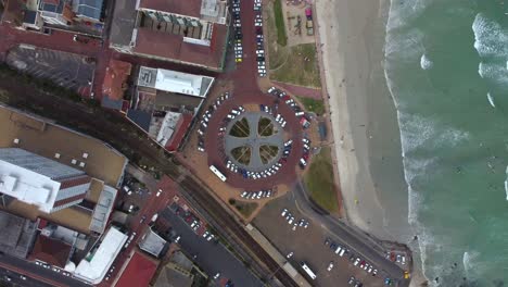 Birds-eye-drone-shot-of-Muizenberg,-Cape-Town---drone-is-descending-over-the-famous-Surfers-Corner