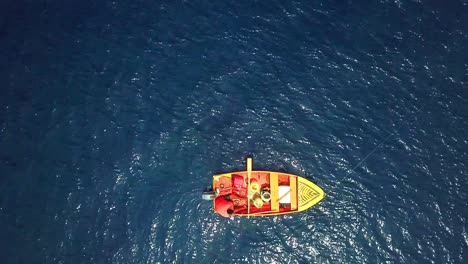 Overhead-view-of-a-fisherman-in-his-red-boat-on-a-sunny-day,-shores-of-Curacao,-Dutch-Caribbean-island