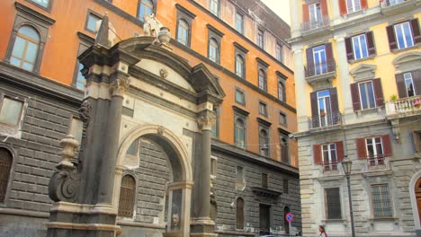 Naples,-Campania,-Italy:-Low-angle-shot-of-a-17th-century-baroque-fountain-called-in-Sellaria-in-Piazzetta-del-Grande-Archivio-in-the-evening-time-with-tourists-going-around