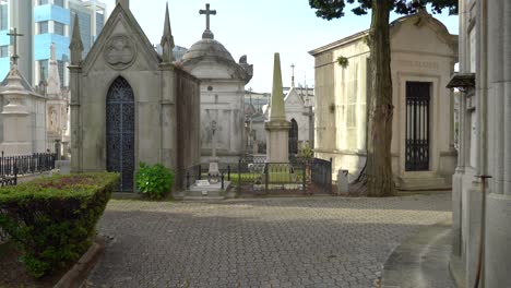 Viejas-Lápidas-En-El-Cementerio-De-Agramonte-Con-Edificios-Comerciales-En-Segundo-Plano.