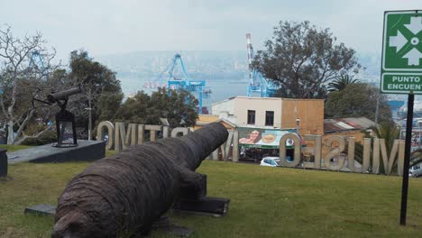 Pan-right-of-an-old-cannon-in-green-field-of-National-Maritime-Museum,-view-from-Cerro-Artilleria,-Valparaiso,-Chile