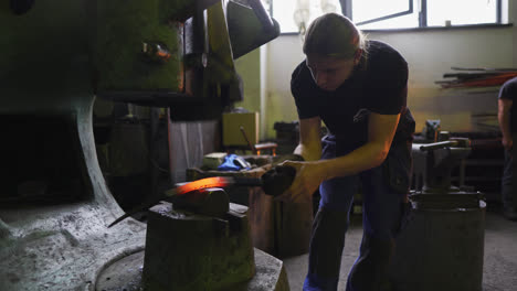 Blacksmith-student-using-power-hammer-to-forge-a-hot-piece-of-metal-at-vocational-high-school