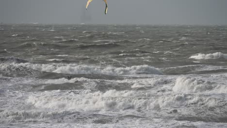 Kitesurfer-jumping-big-waves-during-wild-sea-conditions,-Scheveningen