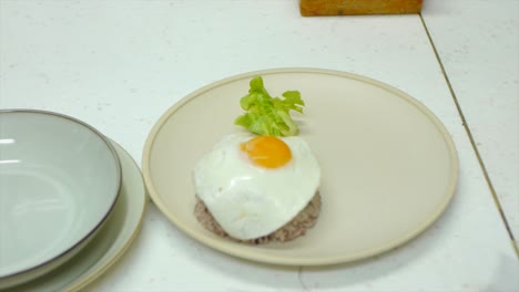 Freshly-fried-egg-being-placed-on-top-of-served-rice-in-kitchen
