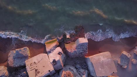 Aerial-birdseye-view-of-abandoned-seaside-fortification-buildings-at-Karosta-Northern-Forts-on-the-beach-of-Baltic-sea-in-Liepaja,-Latvia,-calm-sea,-golden-hour,-wide-angle-point-of-view-drone-shot