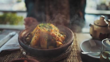 Close-up-shot-of-a-steaming-hot-potato-dish-set-in-a-pottery-bowl-on-a-wooden-table