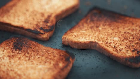 Close-up-shot-of-3-bread-slices-being-toasted-on-a-sheet-pan-in-the-outdoors
