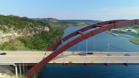 Minor-traffic-moving-from-left-to-right-on-the-Pennybacker-Bridge-with-a-view-of-the-city-of-Austin,-Texas-in-the-upper-right-hand-corner
