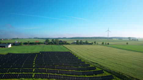 Solar-Panels-Power-Plant-In-Farmland-With-Wind-Turbines-At-The-Background