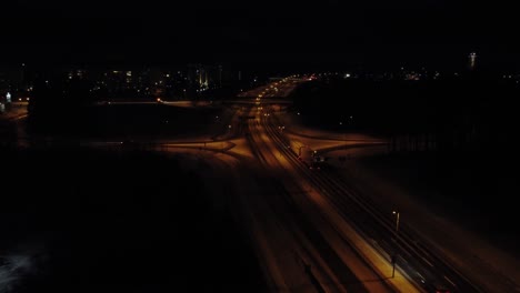 Luftaufnahme-Des-Spärlichen-Nachtverkehrs-Im-Winter-Auf-Der-Autobahn-In-Der-Nähe-Der-Dunklen-Stadt