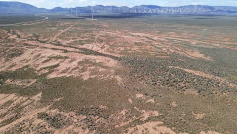 Drone-aerial-pan-up-over-Australian-dry-desert-outback-to-renewable-wind-power-farm-near-mountains