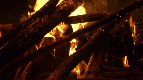 Firewood-burning-with-bright-yellow-flame-and-flying-sparks,-slow-motion