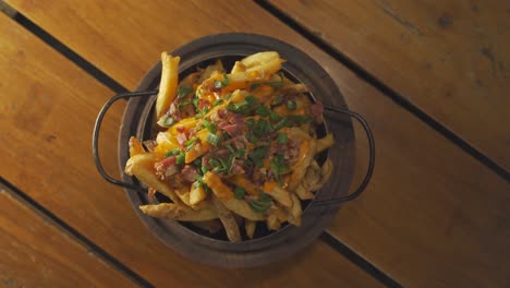 Close-up-shot-of-rotating-bowl-with-Potato-chips-or-French-fries-and-cheddar,-bacon,green-onion