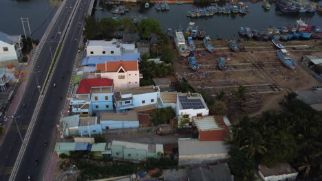 Drone-flying-over-colorful-picturesque-houses-in-river-banks-of-Phan-Thiet-city,-Vietnam