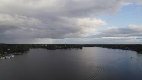 Drone-footage-of-Lake-Mirow-on-an-overcast-day-with-rainbow-in-the-back