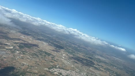 Aerial-cockpit-view-during-a-jet-left-turn-approaching-to-Palma-de-Mallorca’s-airport,-with-a-layer-of-few-clouds