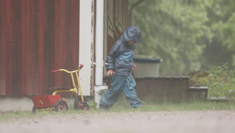 SLOW-MOTION---A-cute-child-plays-with-a-downpipe-in-heavy-rainfall