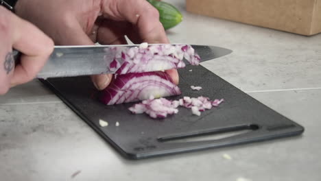 Kitchen-cook-uses-knife-to-dice-red-onion-into-small-pieces,-closeup