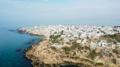 Aerial,-overcrowded-white-houses-by-the-coast-of-a-rural-island