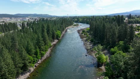 Wide-aerial-view-of-the-Spokane-River-surrounded-by-trees-with-the-Spokane-Valley-off-in-the-distance