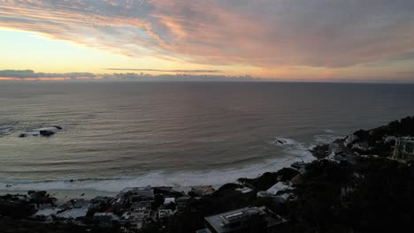 ocean-view-of-South-Atlantic-at-dusk-with-sun-setting-on-horizon-in-Cape-Town,-aerial