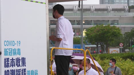 Anwohner-Stehen-Schlange,-Um-PCR-Tests-Auf-Coronavirus-Von-Einem-Lastwagen-Eines-Kommunalen-Testzentrums-Zu-Erhalten,-Um-Die-Ausbreitung-Des-Virus-Und-Eine-Pandemiewelle-In-Der-Nähe-Des-Finanzviertels-Von-Hongkong-Einzudämmen