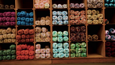 Shelves-displaying-various-colors-of-yarn-in-fabric-factory-store,-dolly-in