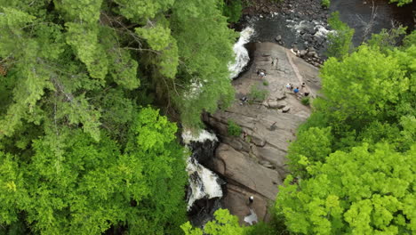 Birds-eye-view-drone-fly-around-arrowhead-provincial-park-capturing-beautiful-Stubb’s-Falls-with-people-resting-on-rock,-enjoying-the-pleasant-natural-environment,-Huntsville,-Ontario,-Canada
